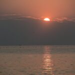 El cautivador amanecer sobre las tranquilas aguas del océano crea una escena tranquila con reflejos y tonos suaves.