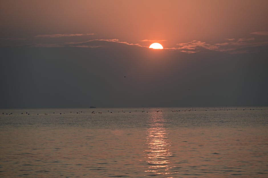 El cautivador amanecer sobre las tranquilas aguas del océano crea una escena tranquila con reflejos y tonos suaves.