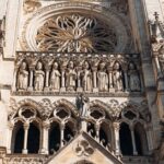 Primer plano detallado de la arquitectura gótica de la Catedral de Amiens, que muestra esculturas ornamentadas y un rosetón.
