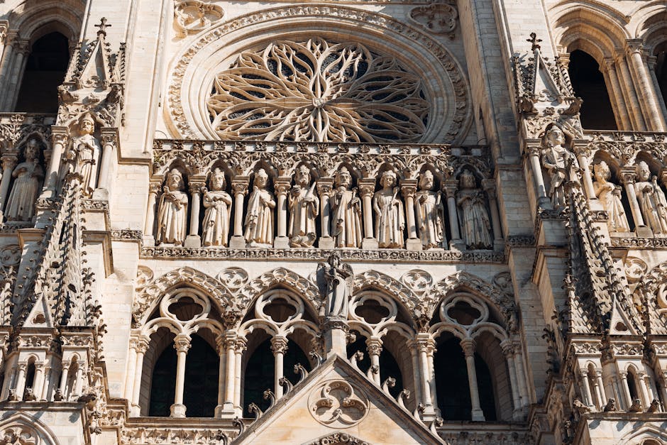 Primer plano detallado de la arquitectura gótica de la Catedral de Amiens, que muestra esculturas ornamentadas y un rosetón.